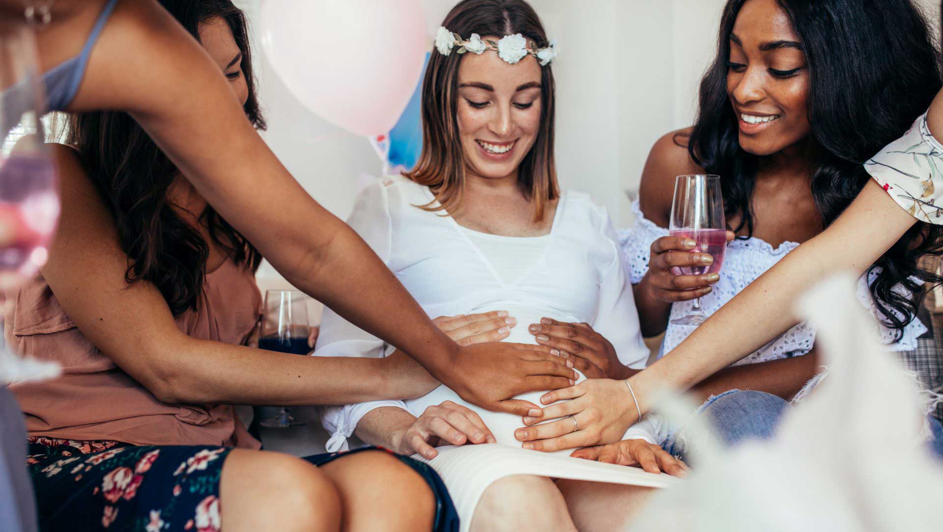Female friends touching tummy of expecting mother